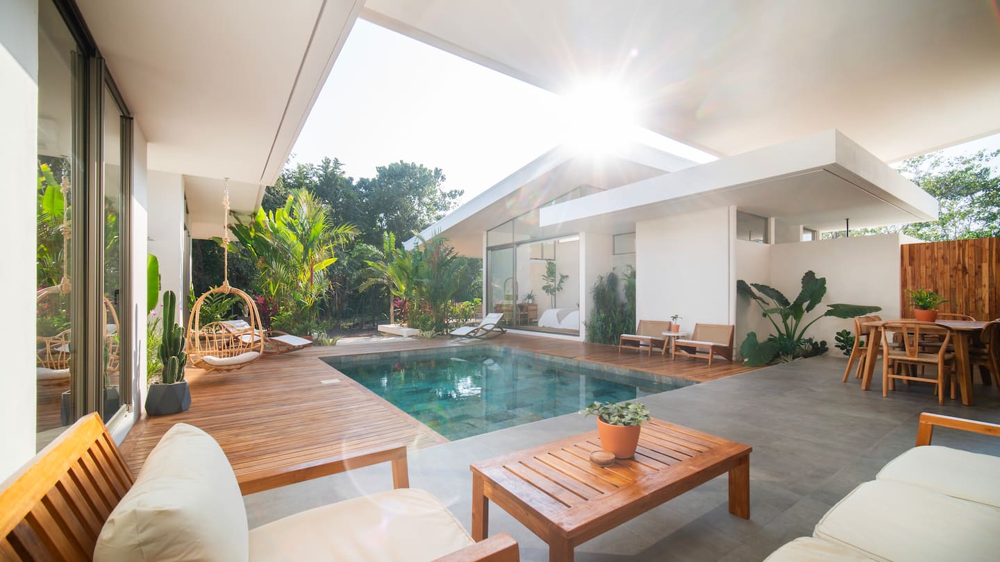 Sunny pool courtyard with hanging rattan chair and teak deck