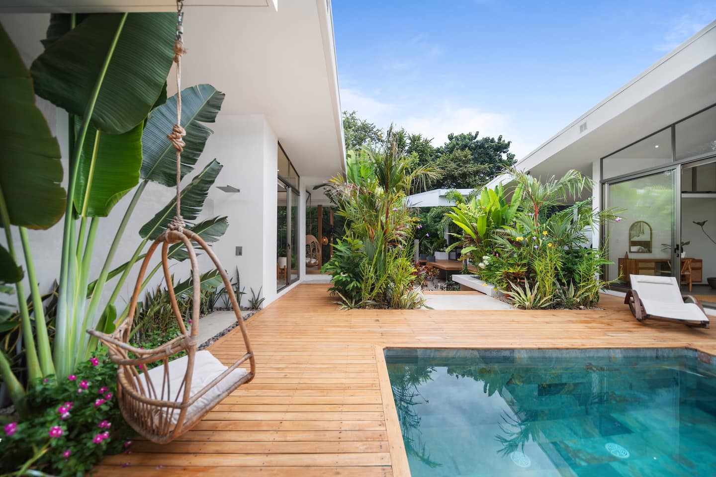 Pool deck with banana palm hanging chair and tropical garden