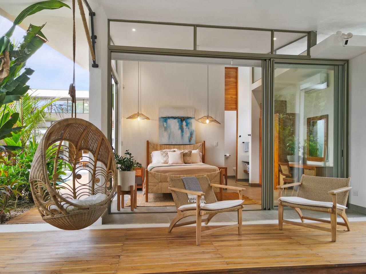 Wicker egg chair on deck with bedroom suite visible through glass doors