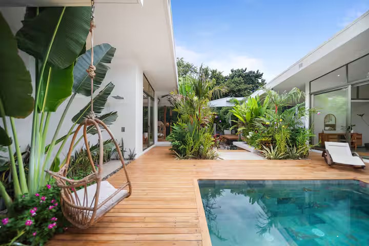 Pool with hanging rattan chair and jungle backdrop